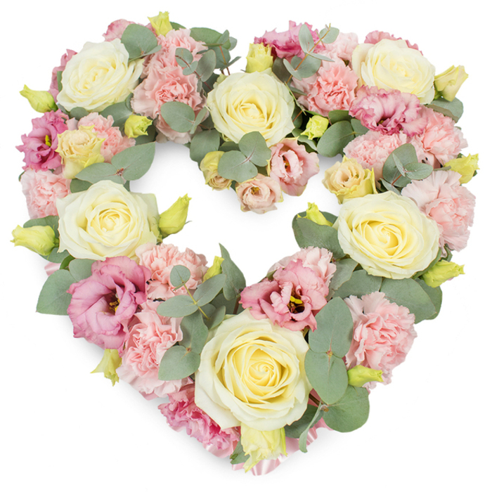 A generously filled, heart-shaped wreath of funeral flowers appears against a crisp white backdrop, every inch covered in soft petals and cool foliage to create a deeply expressive tribute suitable for a service or home gathering in Emerson Park. The heart is sculpted from a careful blend of pastel blooms, with creamy ivory and pale yellow roses acting as the central stars. Their velvety, layered petals spiral outwards from tight centres into full, rounded blooms that feel both elegant and reassuring. Woven snugly around and between these roses are clusters of light pink carnations, their ruffled edges catching the eye with a delicate, almost lace-like texture that softens the entire arrangement. Scattered thoughtfully throughout are lisianthus (eustoma) blossoms in shades of deeper pink and mauve, their slightly more open, cup-shaped flowers adding subtle depth and a hint of refined drama to the design. Silvery-green eucalyptus leaves curl and fan throughout the wreath, their small, rounded shapes and matte finish giving a serene, balanced contrast to the softness of the petals-much like the calm greenery found in quiet corners of Emerson Park. Here and there, small yellow-green buds peek out from between the flowers, suggesting freshly prepared stems and the natural cycle of growth. The heart's outline is clear and symmetrical yet appears soft and plush rather than rigid, evoking tenderness and a sense of being held. This floral tribute conveys love, sympathy, and remembrance, making it an especially comforting choice for funerals, memorial services, or anniversaries, where families wish to honour a loved one with something both beautiful and deeply symbolic.
